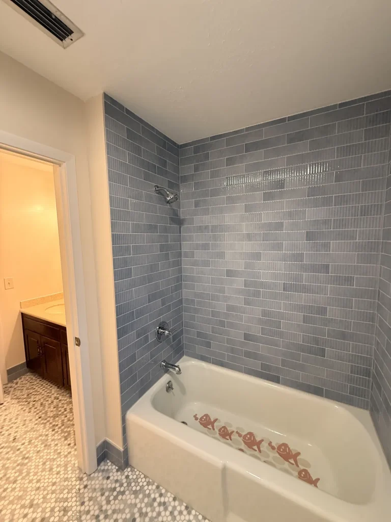 Blue subway tile tub surround with pebble floor