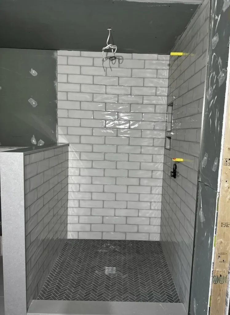 White subway tile shower with hex mosaic floor