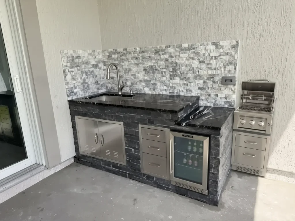 Outdoor kitchen with split-face stone backsplash and stainless doors