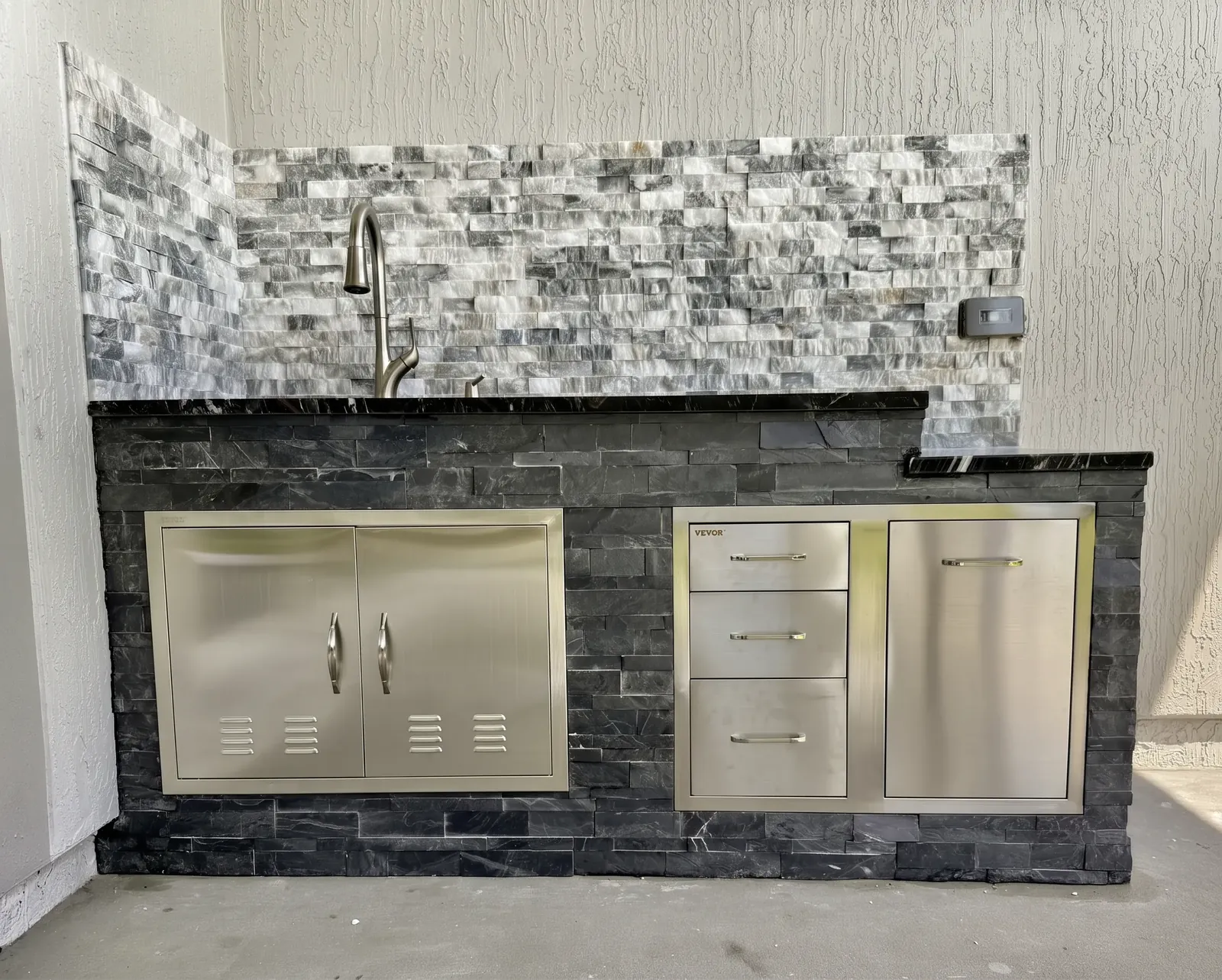 Outdoor kitchen finished in stacked stone with a black granite countertop