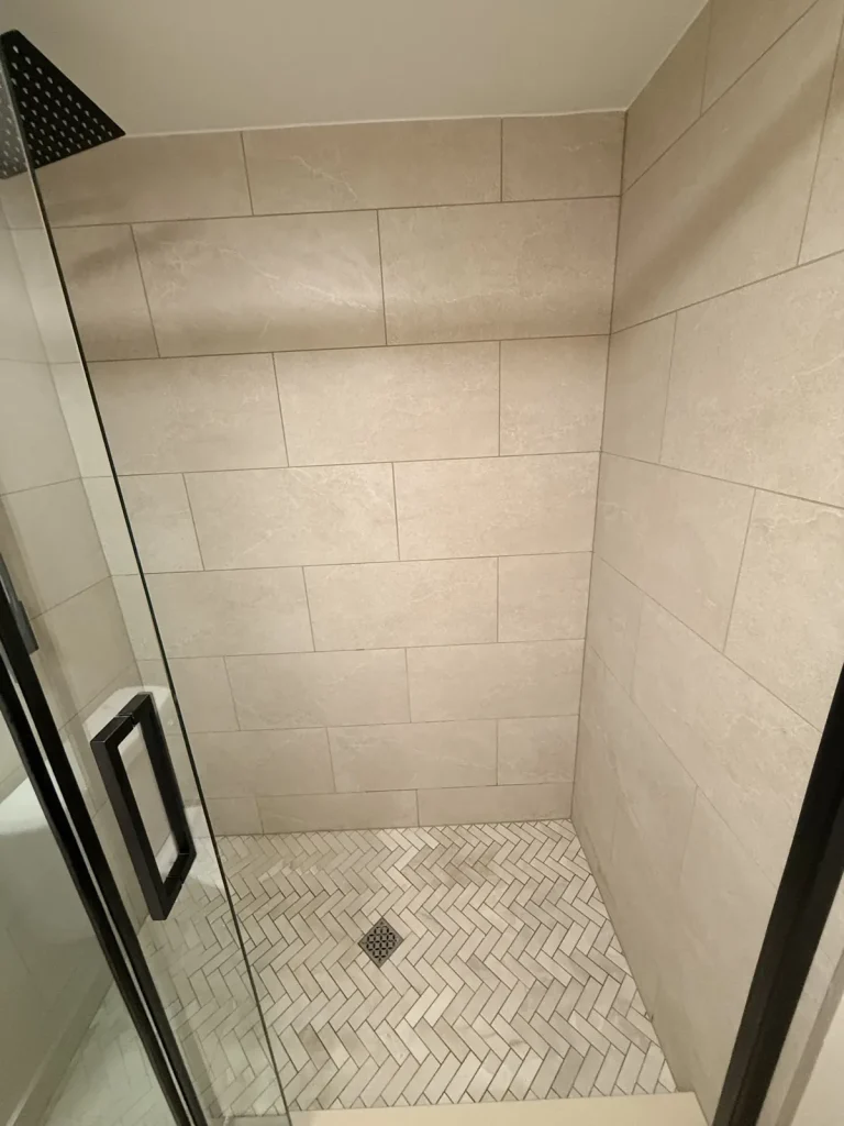 Marble herringbone shower floor with large-format wall tile